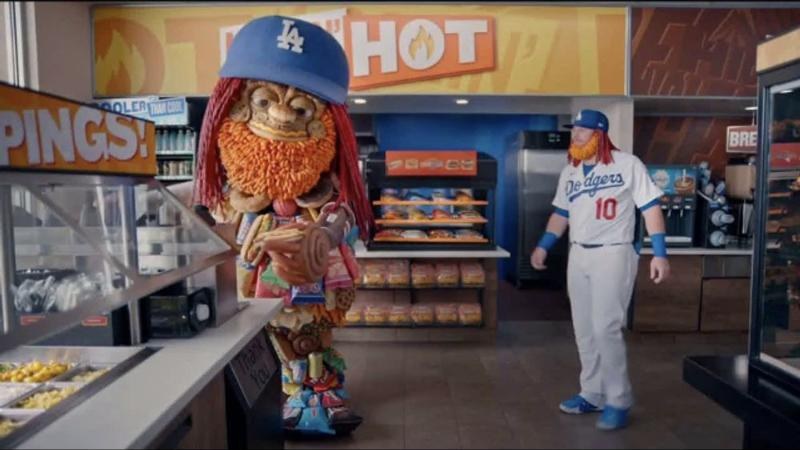 Dodgers third baseman Justin Turner, in uniform number 10, facing ampm mascot Toomgis inside an ampm store