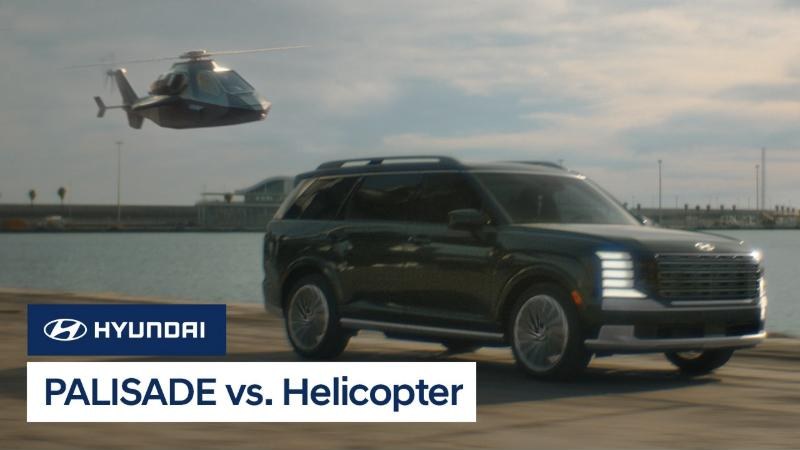 The Palisade Hybrid racing a helicopter along a waterfront